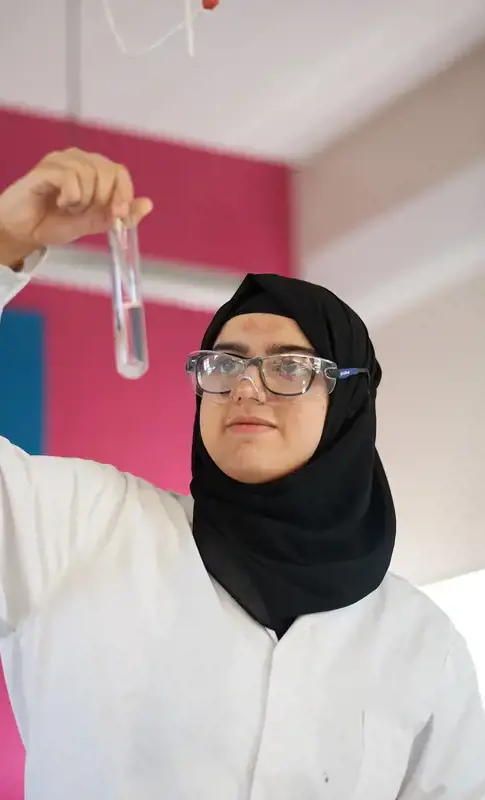 Pupil in science class, holding and examining a test tube