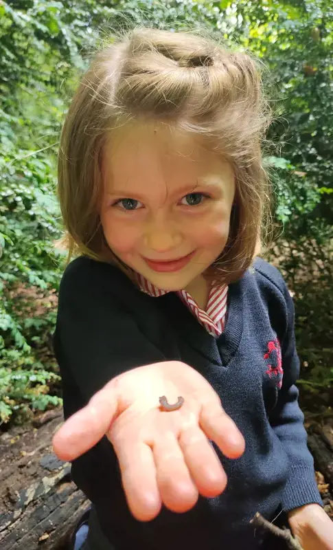 Girl outside holding an insect in the palm of her hand