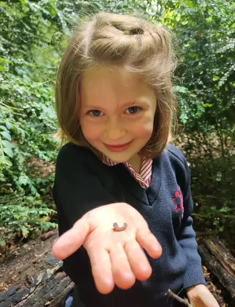 Nursery pupil in garden, holding an insect