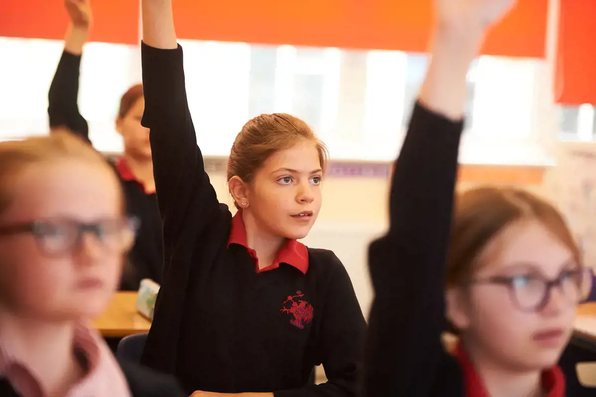 A student in class with her hand raised