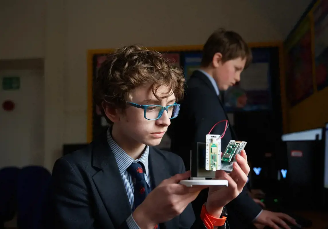 A student holding an electronics project