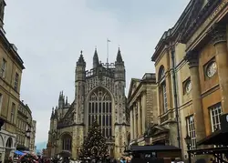 A street in oxford leading to a chapel in the background.  There is a Christmas tree near the chapel and people walking the street.